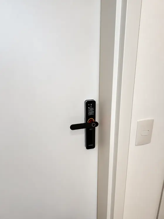 Fechadura digital preta com maçaneta e leitor de digital em porta branca
