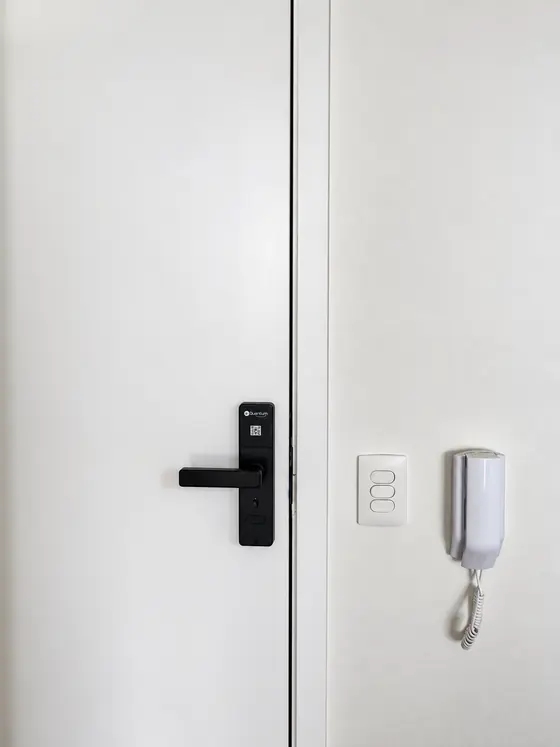 Fechadura digital Kuantum preta com maçaneta em porta branca
