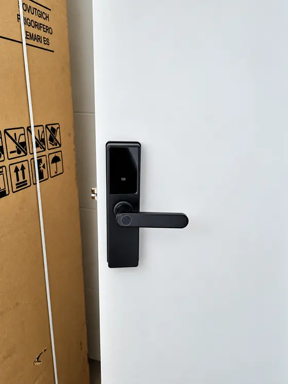 Fechadura digital preta com maçaneta em porta branca de apartamento novo