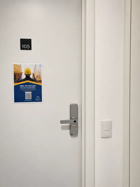 Fechadura digital prata em porta branca de prédio novo